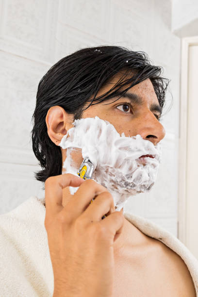 istock young man shaving his beard with a razor 1418614242