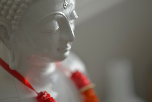 Antique white buddha lit by natural sunlight: Selective focus.