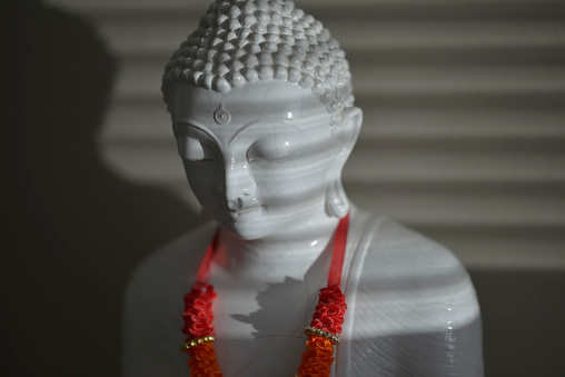 Antique white buddha lit by natural sunlight.