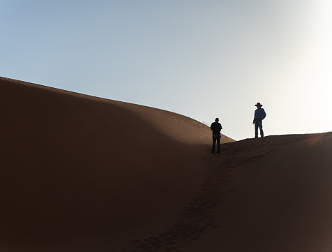 A Man is walking through virgin dunes at sunrise in the Gobi Desert in southern Mongolia.