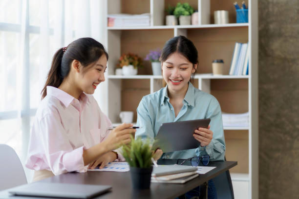 istock Two beautiful Asian businesswomen using digital tablet consulting and analyzing information in office work. 1418641417