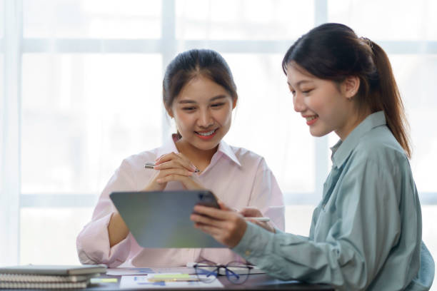 istock Two beautiful Asian businesswomen using digital tablet consulting and analyzing information in office work. 1418641418