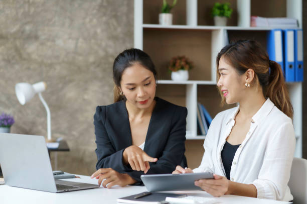 istock Two beautiful Asian businesswomen using digital tablet consulting and analyzing information in office work. 1418641433