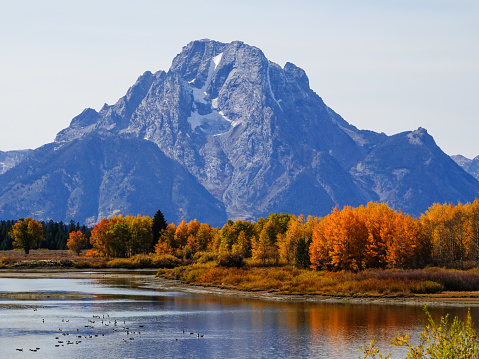 Peaks of Grand Teton National Park in autumn with a lake in the foreground.