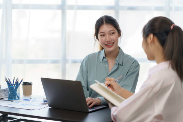 istock Two young Asian businesswomen discuss with new startup project Idea presentation, analyze planning and financial statistics and investment market on laptop computer at office. 1418651955