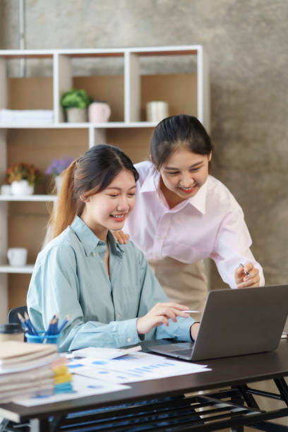 istock Two young Asian businesswomen discuss with new startup project Idea presentation, analyze planning and financial statistics and investment market on laptop computer at office. 1418651956