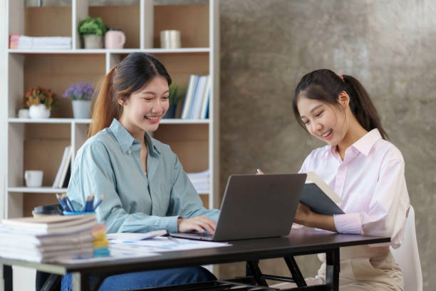 istock Two young Asian businesswomen discuss with new startup project Idea presentation, analyze planning and financial statistics and investment market on laptop computer at office. 1418651957