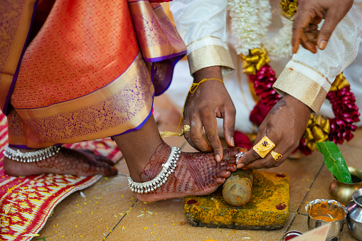 Indian couple hand close up perform toe ring ceremony in Indian wedding.