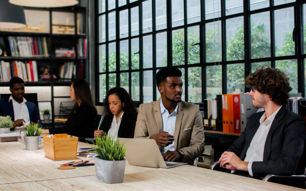istock Diverse and multiracial smart businesspeople wearing formal suits, using computer, working, meeting, brainstorming together about company marketing plan or creative idea in indoor modern office. 1418666842