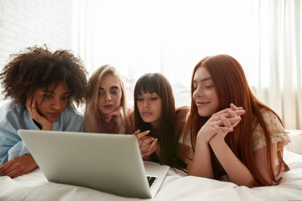istock Girlfriends watching laptop on bed at pajama party 1418674937
