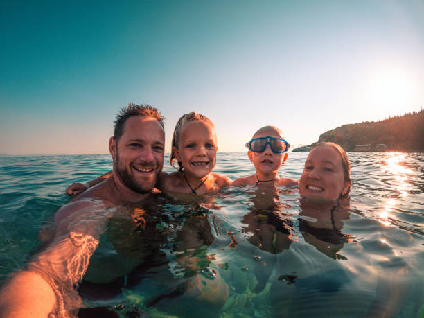 istock Smiling Family with Two Boys Looking at Camera While in the Beach 1418682327