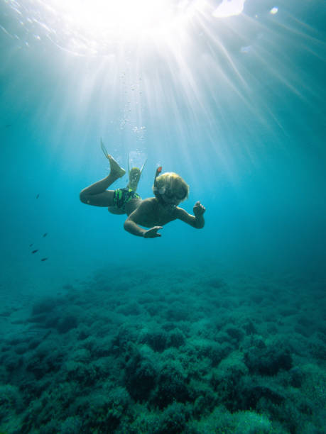 istock Explorer Child Observing Rocks While Swimming in the Sea 1418682369