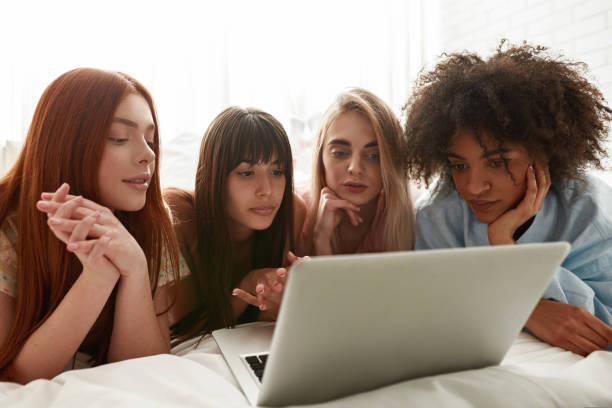 istock Young multiethnic girlfriends watch laptop on bed 1418683013
