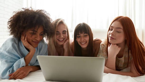 istock Young positive girlfriends watching laptop on bed 1418683307