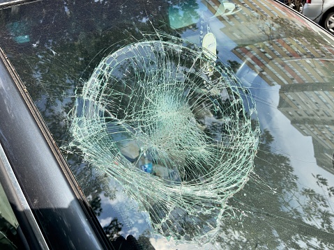 Broken car windshield, cracks diverge from the center of impact