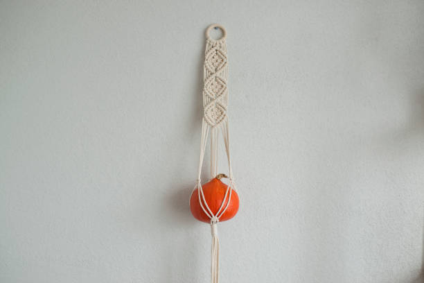 istock Pumpkin hanging in a macrame planters on the wall, free space 1418690446