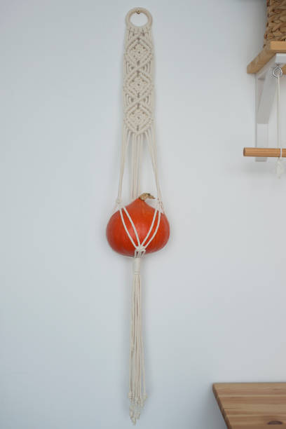istock Pumpkin hanging in a macrame planters on the wall, free space 1418690673