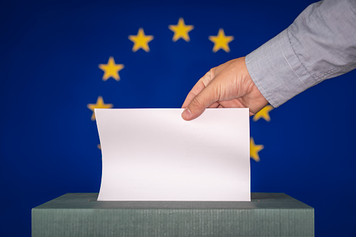 man putting ballot in a box during elections in european union against the background of the European flag