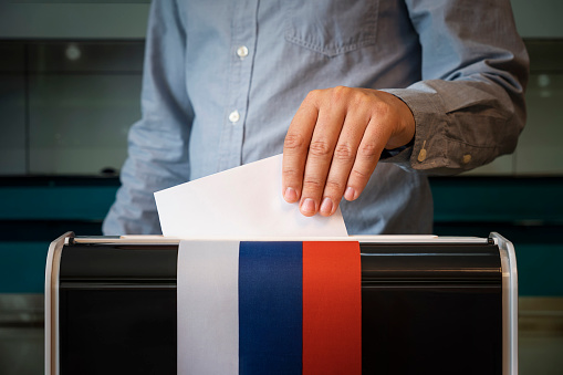 male hand of a voter lowers the ballot in the ballot box. concept of state elections. voters to vote on a single voting day in Russia at a polling station