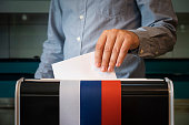 voters to vote on a single voting day in Russia at a polling station. male hand of a voter lowers the ballot in the ballot box. concept of state elections