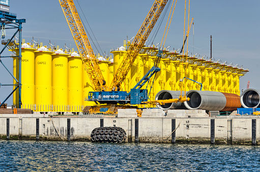 Rotterdam, The Netherlands, August 23, 2022: large yellow foundation pieces future offshore wind turbines waiting for shipping on Maasvlakte industrial area