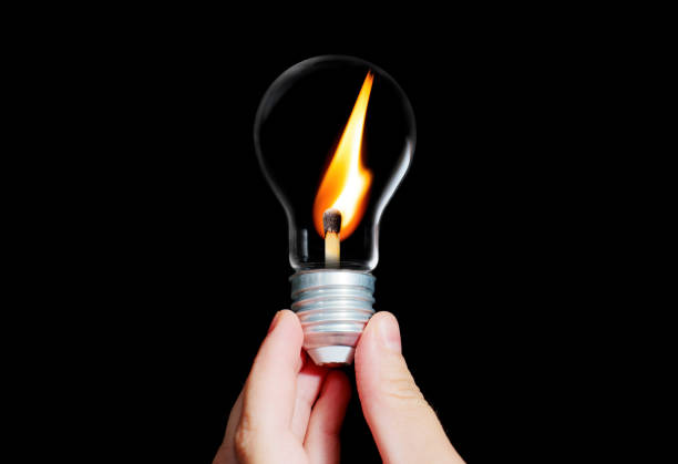 istock Light bulb with a burning matchstick in hand 1418723494