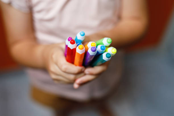 Closeup of hands little preschooler girl holding colorful pencils . Playful child with pencils. Imagination and creativity at school concept. stock photo