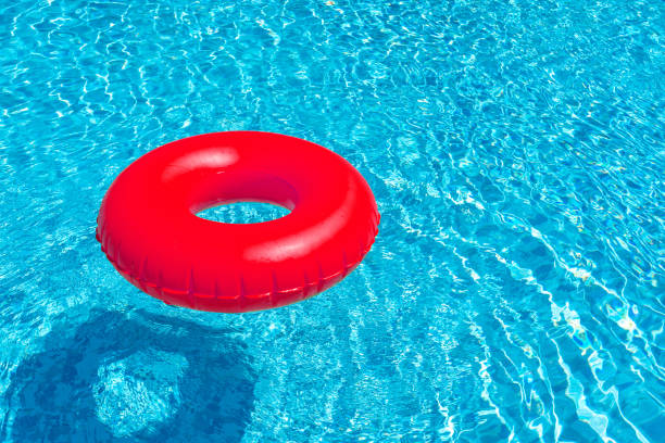 czerwony pierścień unoszący się w niebieskim basenie. nadmuchiwany pierścień, koncepcja odpoczynku - swimming tube inflatable circle zdjęcia i obrazy z banku zdjęć