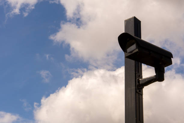 istock Closeup video surveillance camera blue clouds 1418731078