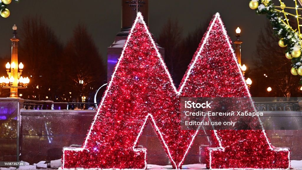 The sign of the Moscow metro in the New Year decorations and multi-colored garlands. The sign of the Moscow metro in the New Year decorations and multi-colored garlands in snowy weather. Christmas street in Moscow. Moscow - Russia Stock Photo