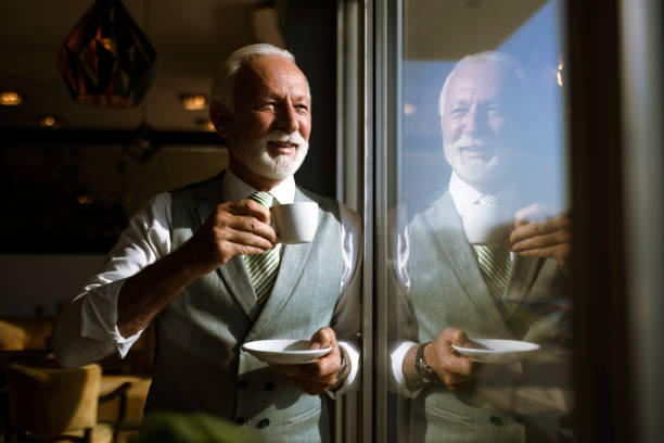 istock Senior businessman drinking coffee in a restaurant standing next to window 1418736358