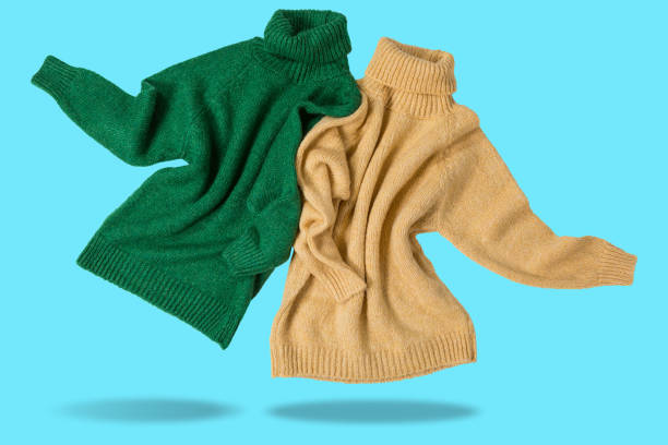 Two wool sweaters, yellow and green, as if dancing in pairs, concept, on a cyan background
