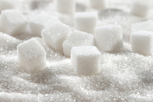 White granulated sugar and refined sugar cubes close-up.