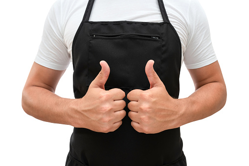 Torso of a man in a black apron shows thumbs up on a white isolated background. Chef or waiter concept mockup.
