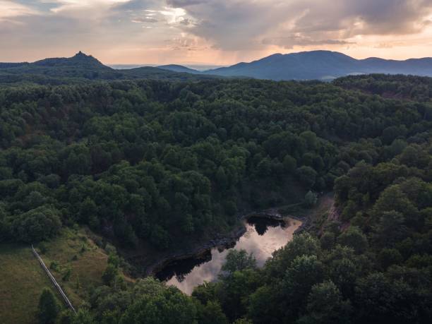 istock Small lake surrounded by forested mountains during sunset 1418744811