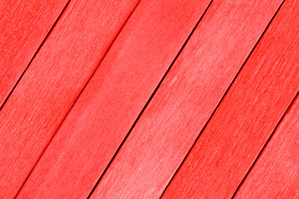 Beautiful wooden boards in red color. Textured background made from red boards. The wooden planks are painted red and arranged diagonally. Colorful red detailed background.