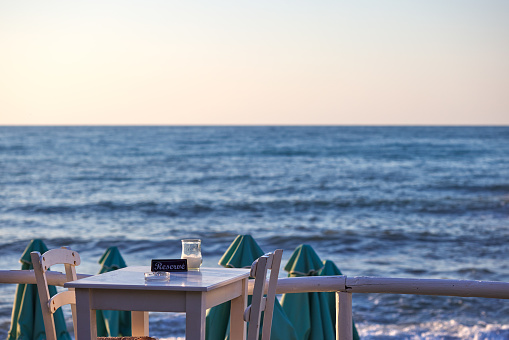 Empty reserved table at a greek taverna and the sea in background in Chania Crete - Greece