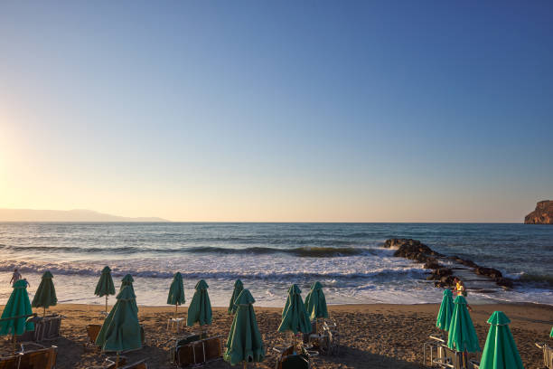Empty sunbeds and umbrellas on the beach at sunset time in Chania Crete - Greece