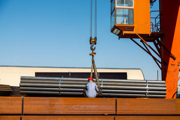 Worker preparing stack of metal pipes for transporting with gantry crane in the steel factory