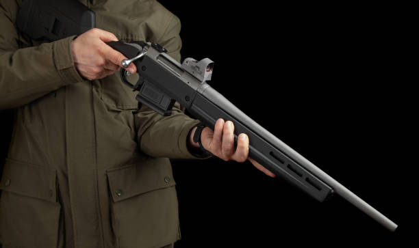un homme vêtu d’une veste kaki tient un fusil à verrou avec un viseur réflexe dans les mains. chasseur avec des armes. fond sombre. - eye bolt photos et images de collection