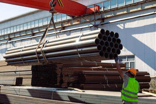 istock Worker transporting stack of metal pipes with gantry crane 1418758381