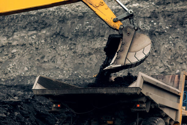 istock Excavator loads coal into the back of a heavy mining dump truck. Open pit coal mining. 1418761231