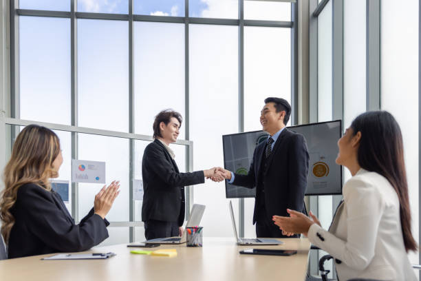 geschäftsgruppe in der besprechung mit händedruck für business-deal-vereinbarung oder feier des erfolgs im modernen büro des sitzungssaals - ceo greeting suit meeting stock-fotos und bilder