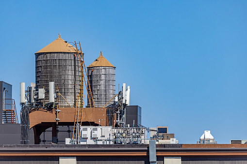 Long Island City, Queens, New York, NY, USA - July 10th 2022: Traditional cedar wooden water storage tanks against a clear blue morning sky