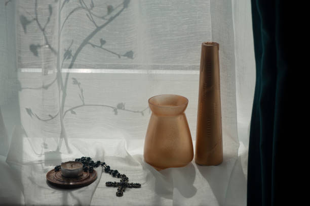 istock Vases on the windowsill create a mood.Cross, lamp, shadow drawing from the window. 1418764308