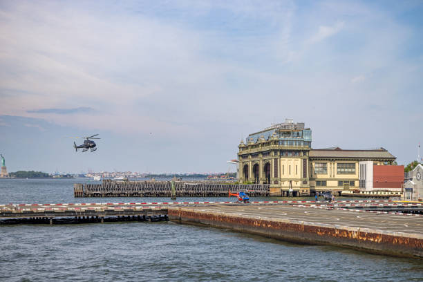 Manhattan, New York, NY, USA - July 9th 2022: The Staten Island ferry terminal on the south end of Manhattan and an approaching helicopter seen from a boat on East River