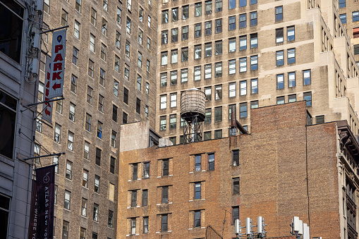 Manhattan, New York, NY, USA - July 9th 2022: Traditional wooden storage water tank on a roof in front of facades of high rise skyscrapers in the center of New York