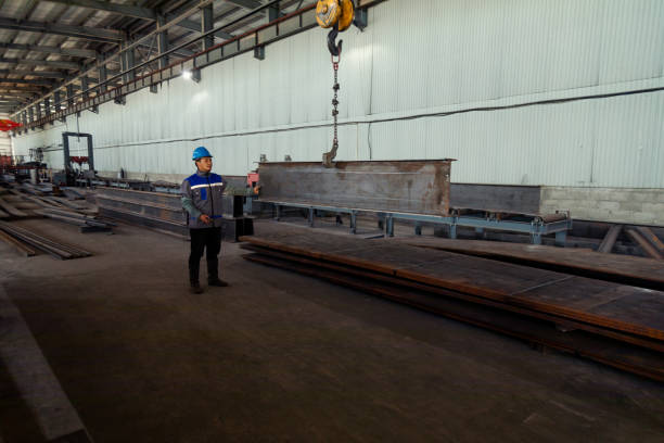 istock Worker receiving a metal bar from crane in warehouse 1418766435