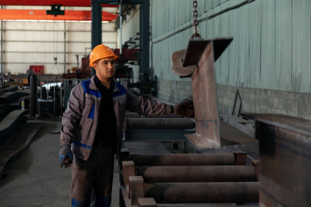 istock Worker receiving a metal bar from crane in warehouse 1418766475