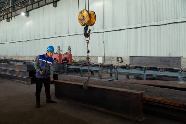 istock Worker receiving a metal bar from crane in warehouse 1418767548